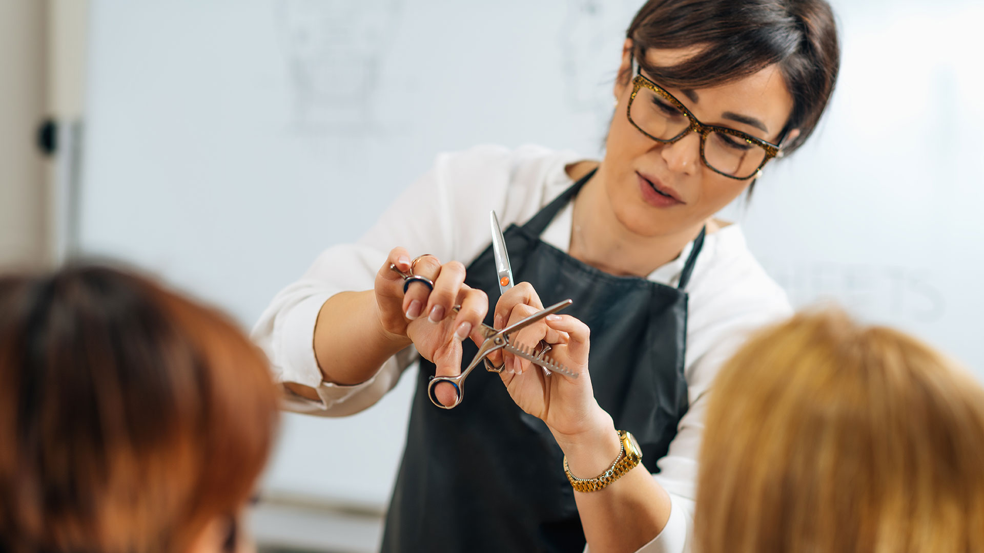 Photo of women teaching people how to use haircut tools.