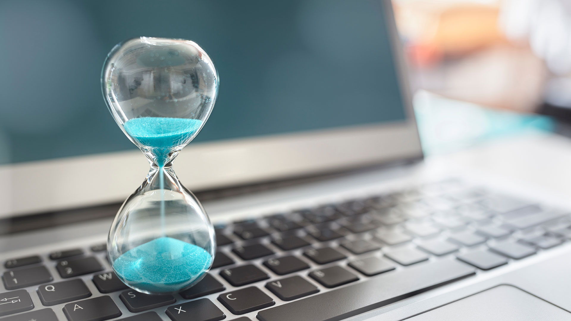 Hourglass on top of laptop keyboard.