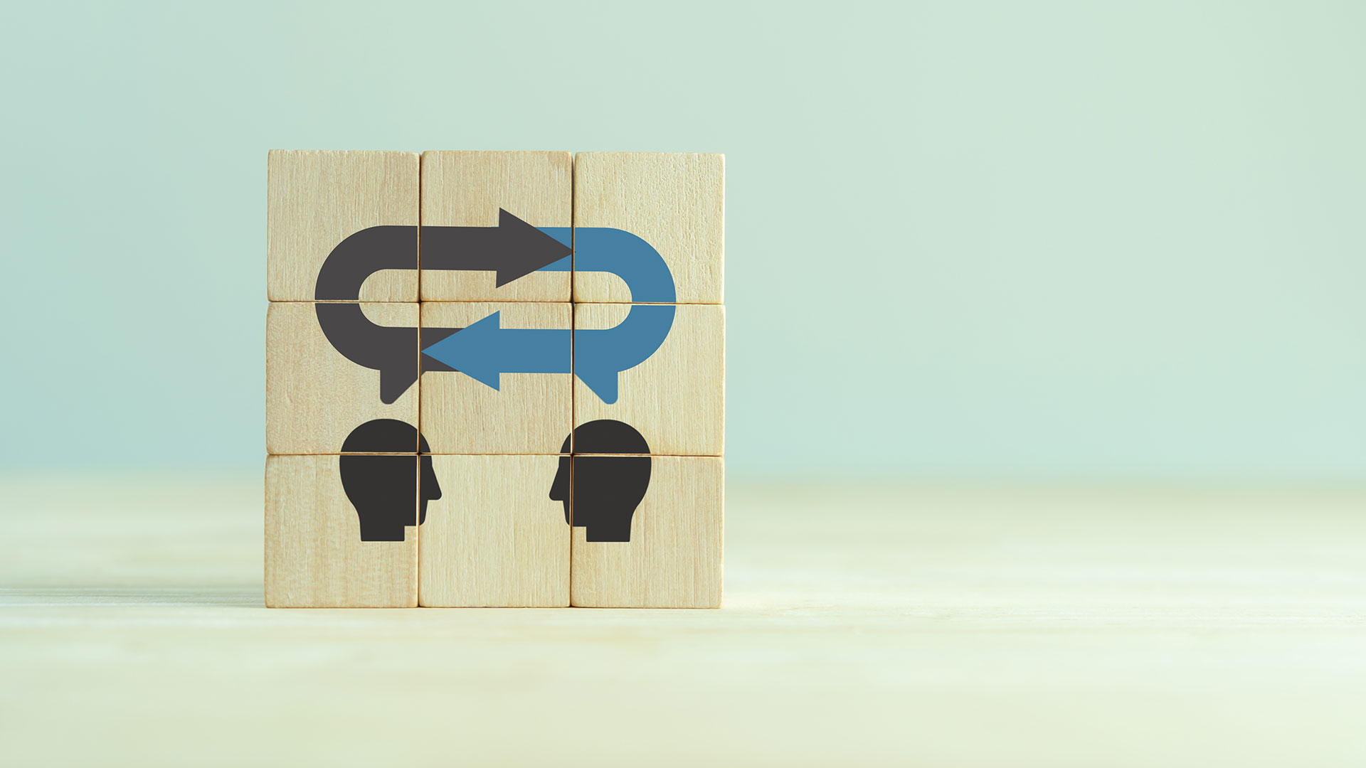 Photo if blocks stacked on top of each other to form an image with two heads with a loop above them implying a feedback process.